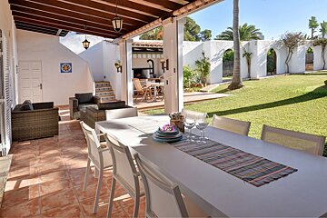 A patio with a table and chairs with plates and glasses on it