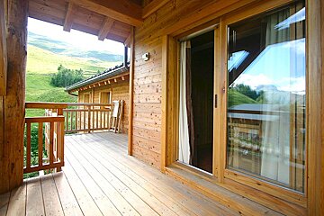 A wooden balcony with a sliding glass door