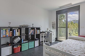 A child 's bedroom with a bed a desk and a shelf filled with books and toys