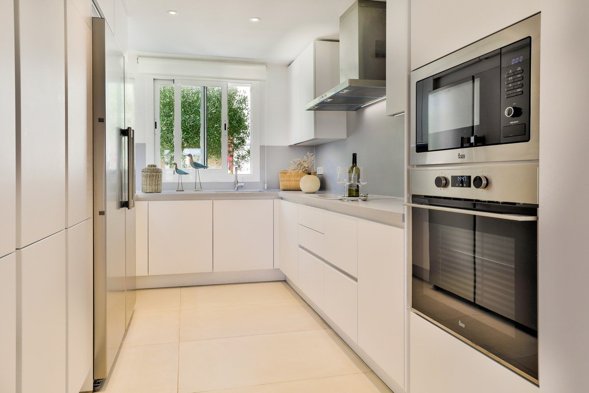A kitchen with white cabinets and stainless steel appliances including a microwave oven