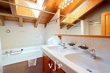 A bathroom with two sinks and a bathtub with the letters vjp on the counter