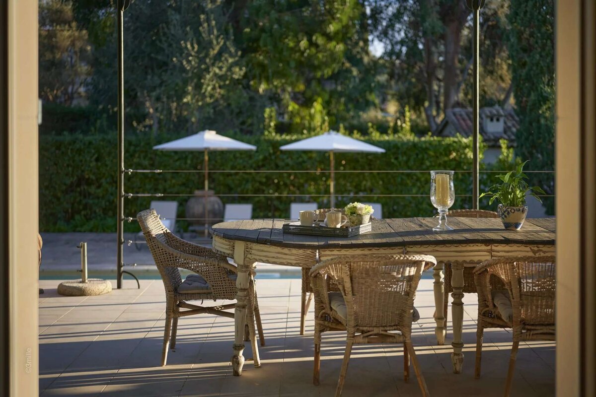 A table and chairs on a patio with umbrellas in the background