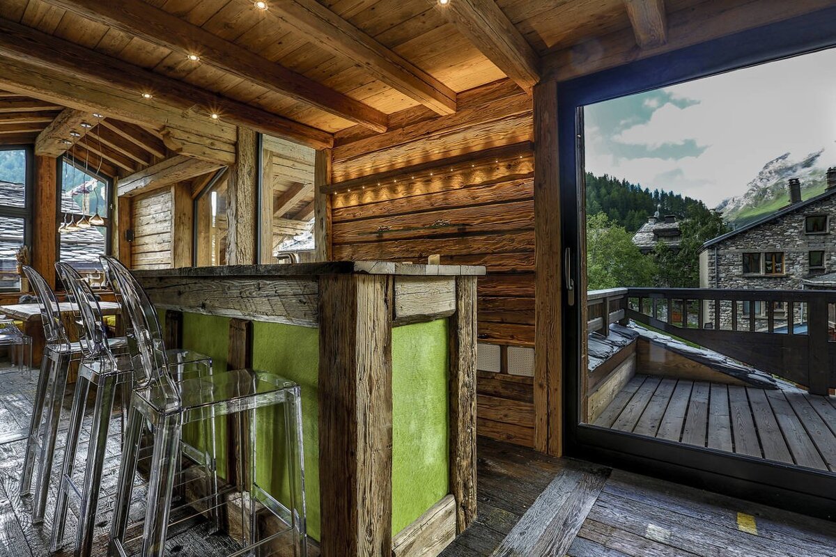 A wooden bar with clear chairs in front of it