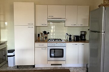 A kitchen with white cabinets and a silver refrigerator