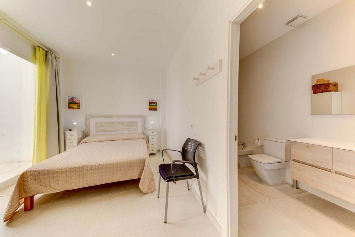 A bedroom with a bed and a chair next to a bathroom