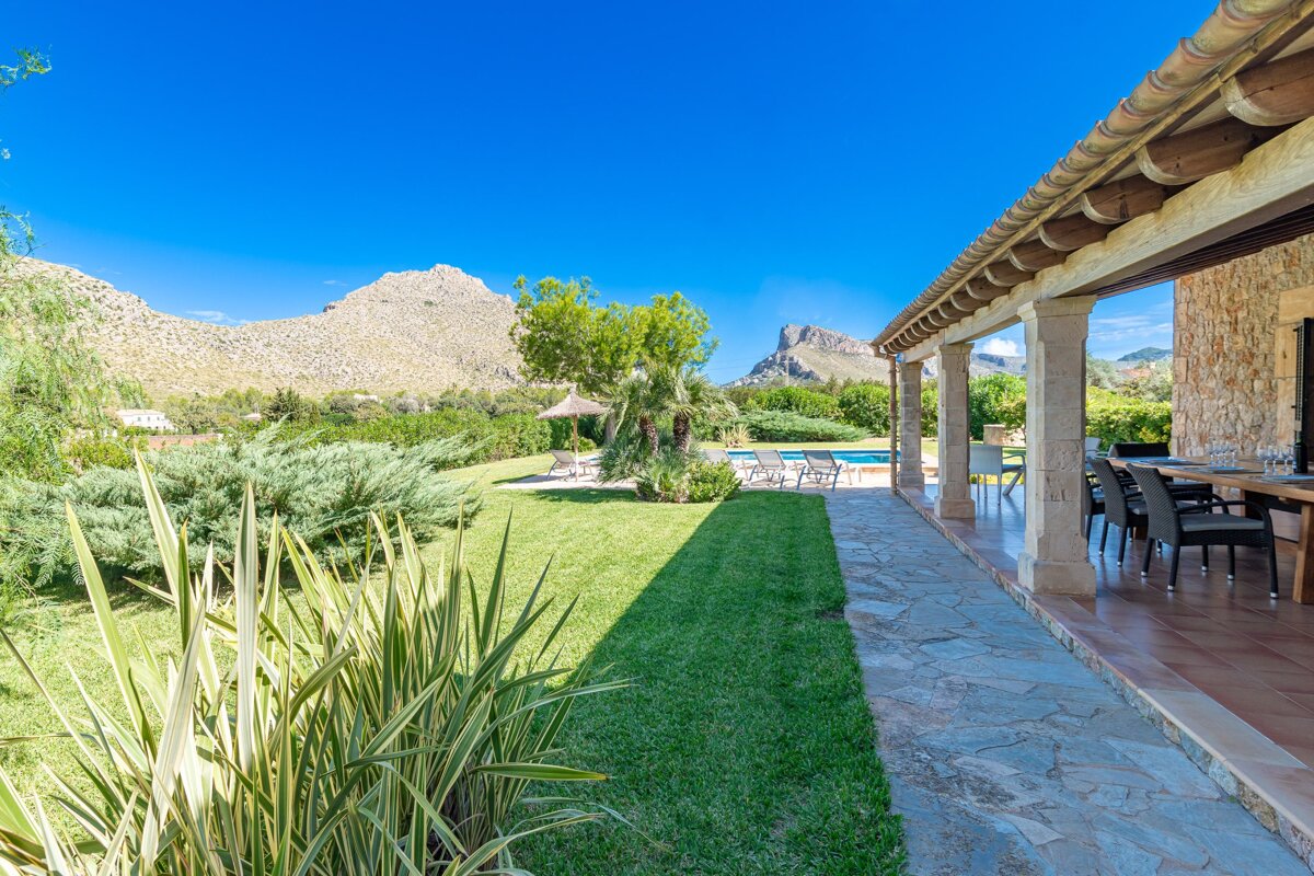 A patio with a table and chairs and a mountain in the background