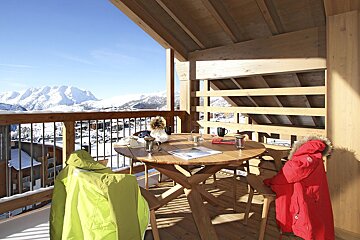 A balcony with a table and chairs with a mountain in the background