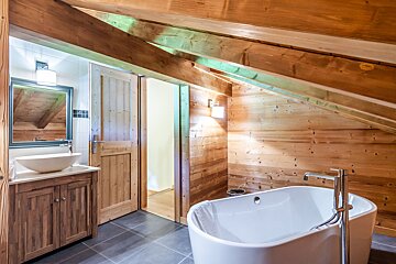 A bathtub in a bathroom with a wooden wall