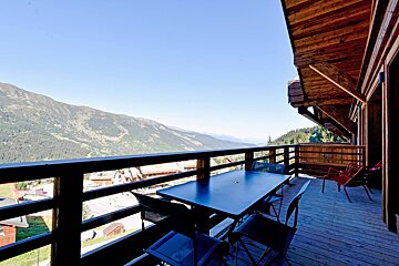 A table and chairs on a balcony overlooking mountains