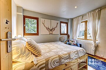 A bedroom with a large bed and a painting of a deer on the wall