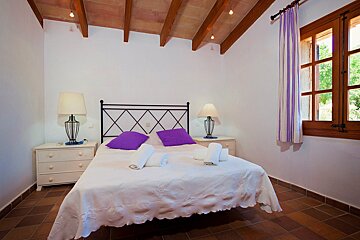 A bedroom with a white bed and purple pillows