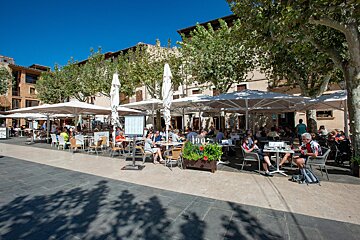 People sit at tables under umbrellas at a restaurant