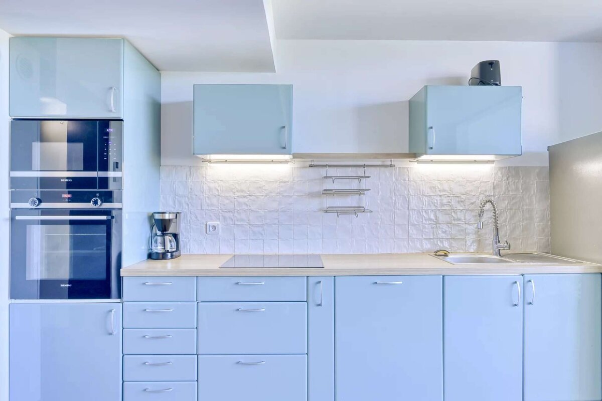 A kitchen with blue cabinets and a coffee maker