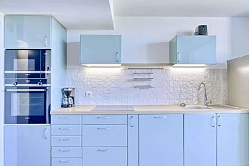 A kitchen with blue cabinets and a coffee maker
