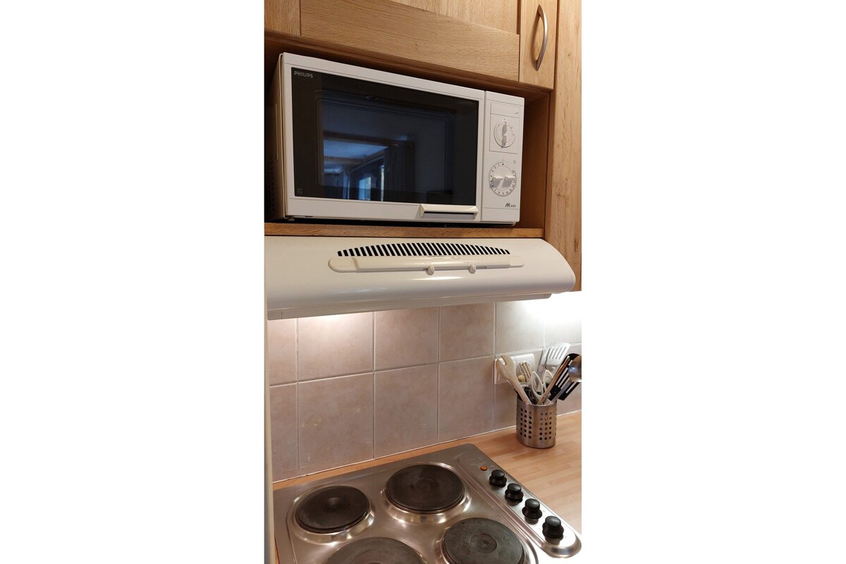 A lg microwave sits above a stove in a kitchen