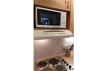 A lg microwave sits above a stove in a kitchen