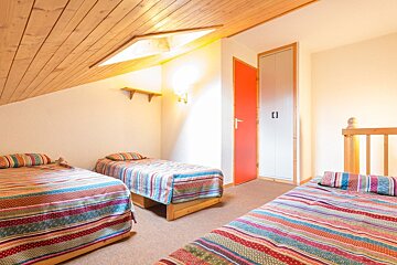A bedroom with three beds and a red door