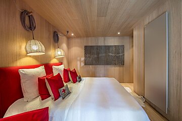 A bedroom with red pillows and a painting on the wall