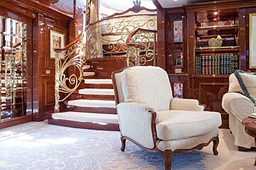 A chair sits in front of a staircase with a wrought iron railing
