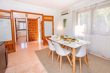 A dining room table with a bowl of fruit on it