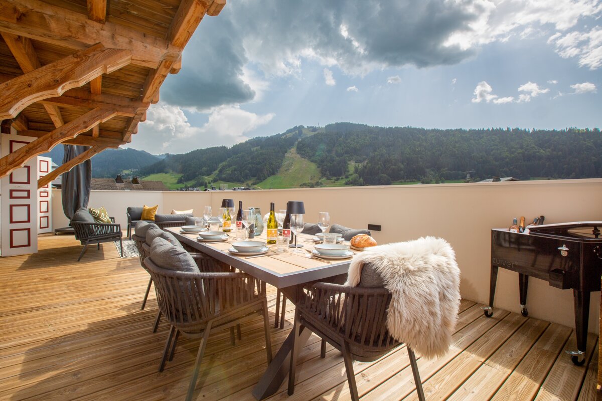 A table and chairs on a deck with a view of mountains