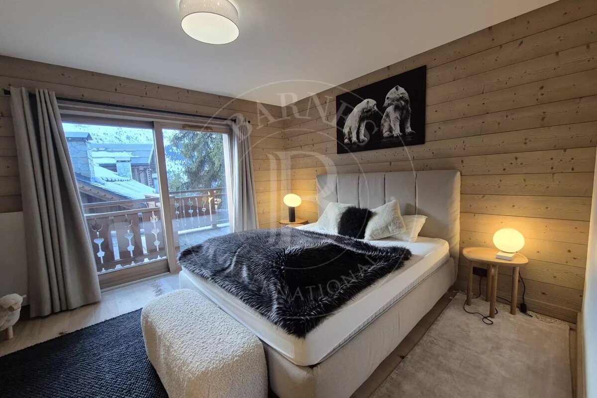 A modern, wood-paneled bedroom featuring a large bed with a faux fur blanket, a balcony overlooking mountains, and polar bear artwork.