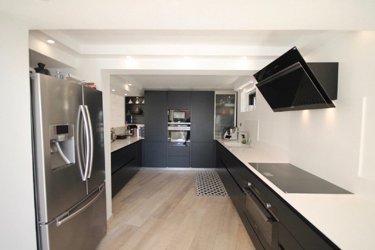 A kitchen with black cabinets and a stainless steel refrigerator