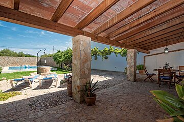 A patio with a table and chairs under a wooden roof