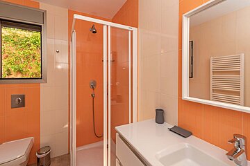 A bathroom with orange tiles and a walk in shower