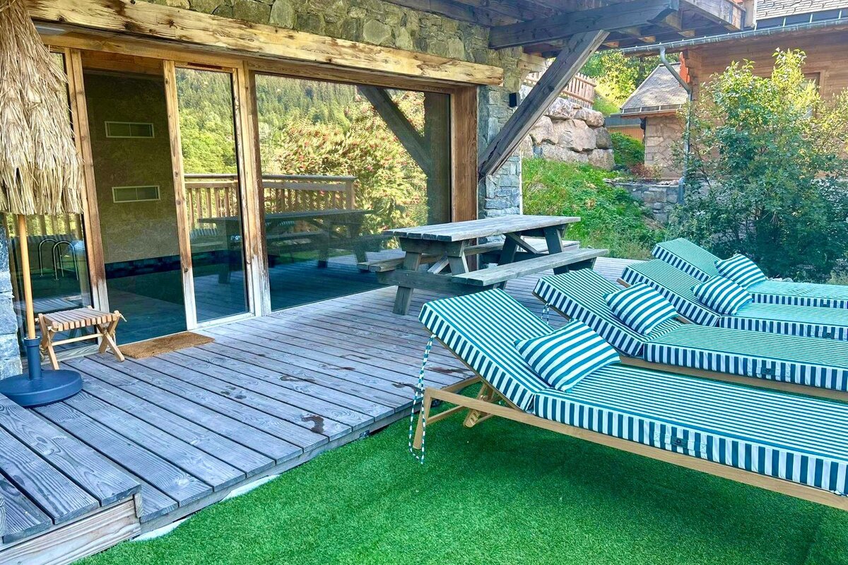 A deck with striped lounge chairs and a picnic table