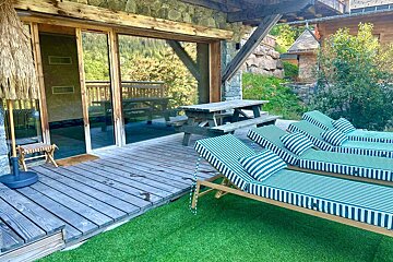 A deck with striped lounge chairs and a picnic table