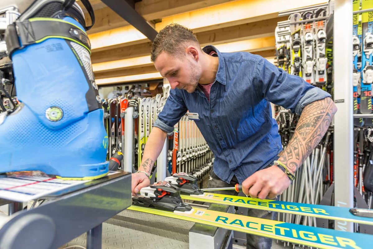 A man is working on a pair of racetiger skis