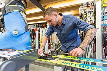 A man is working on a pair of racetiger skis