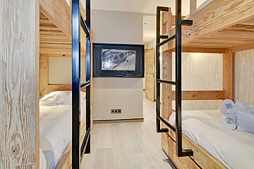 A room with bunk beds and a tv on the wall