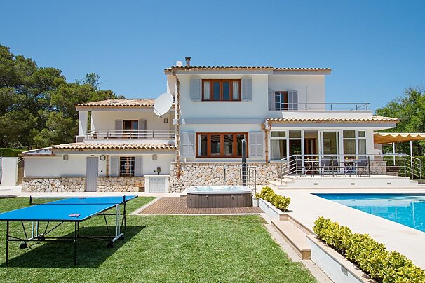 A large house with a pool and ping pong tables in front of it