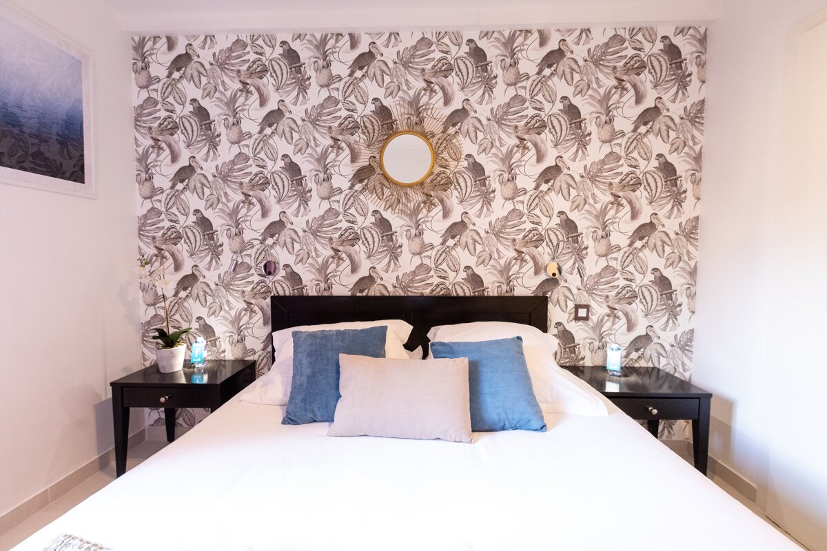 A bedroom with a bed and a wall with birds on it