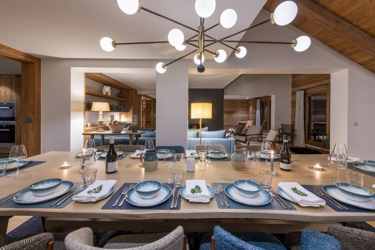 A dining room table with a bottle of wine on it