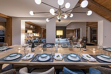 A dining room table with a bottle of wine on it