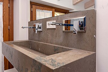 A bathroom sink with three faucets and a mirror