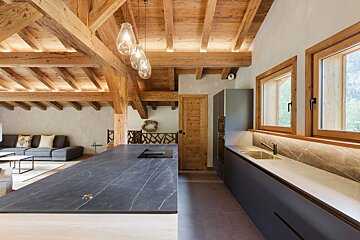 A kitchen with a black counter top and wooden beams