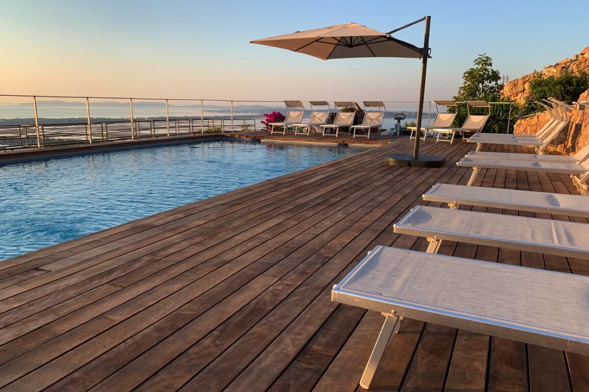 A swimming pool surrounded by deck chairs and an umbrella
