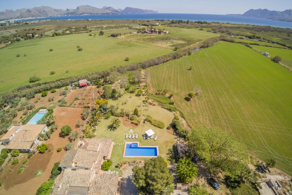 An aerial view of a lush green field with mountains in the background