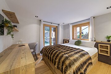 A bedroom with a large bed and a wooden desk