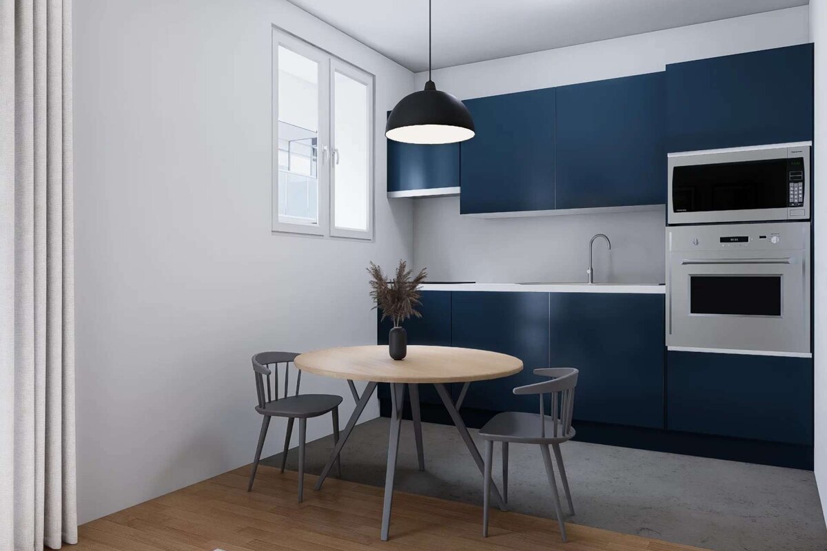 Modern kitchen with navy cabinets, white walls, stainless steel appliances, a round wooden dining table with two grey chairs, and a window.
