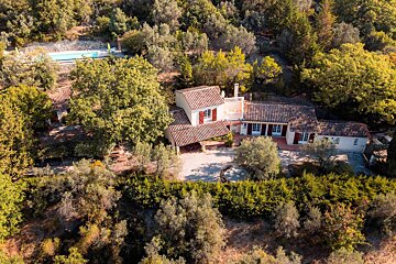 An aerial view of a house surrounded by trees and a pool