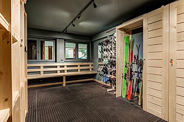 A bunch of skis are lined up in a room with a bench