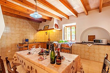 A kitchen with a table and chairs and a bottle of alcohol on the table