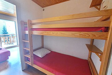 A bunk bed with red sheets and a white pillow