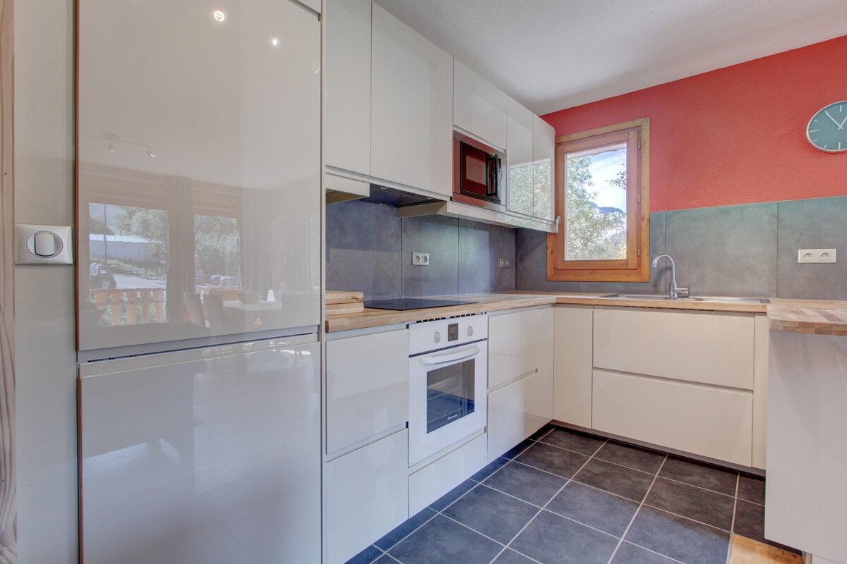 A kitchen with white cabinets and a clock on the wall
