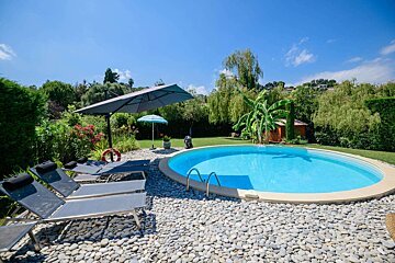 A swimming pool surrounded by chairs and a large umbrella